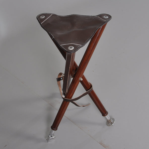 Foldable Hunting Chair in heavy brown leather. Three legs in brown stained wood. Leather carrying strap. 